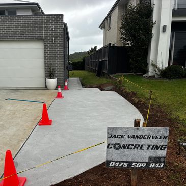 Newly poured concrete driveway with caution cones and signage.