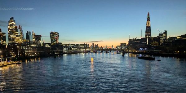 Evening skyline of London with river and illuminated buildings.