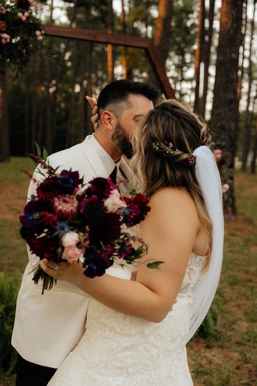 Bride and groom kissing and holding flowers