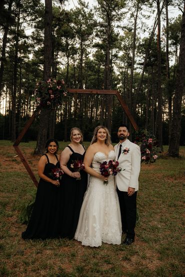 Bridal party standing in front of a wedding arch