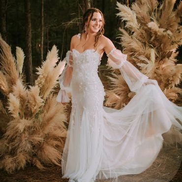 Bride holding dress in front of pampas grass flowers arrangements