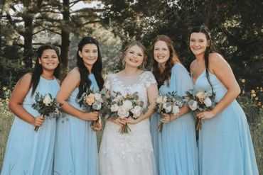 Bride and bridesmaids smiling and holding flowers
