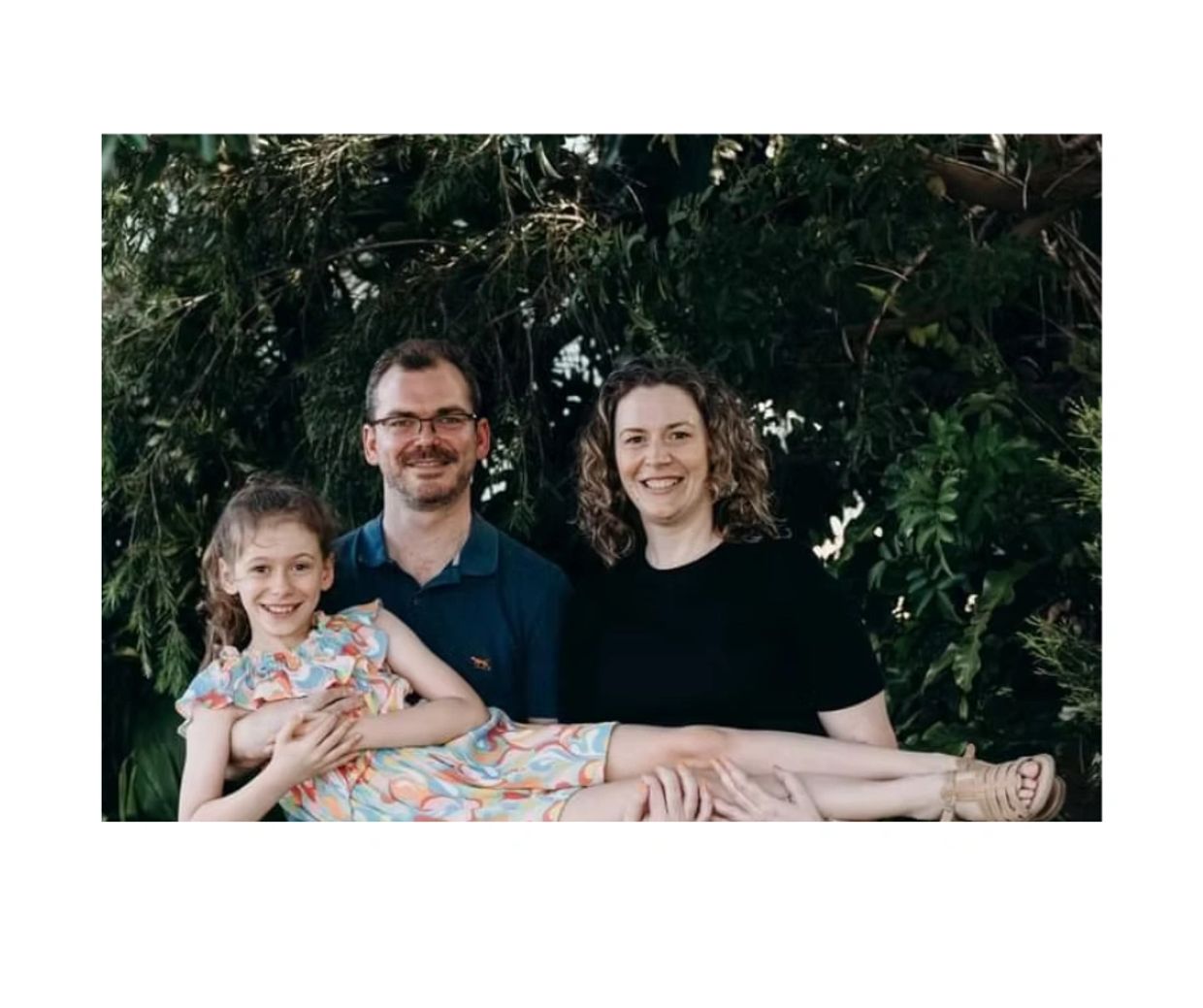 Family photo, parents and their daughter, green foliage, garden, happy