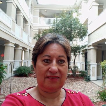 Mujer de mediana edad en un vestíbulo con plantas.