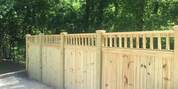 Newly installed wooden privacy fence with vertical slats and decorative top design.