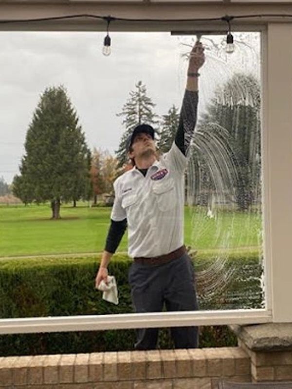 Man cleaning a large window outdoors.