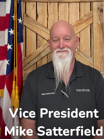 Vice President Mike Satterfield smiling in front of an American flag.