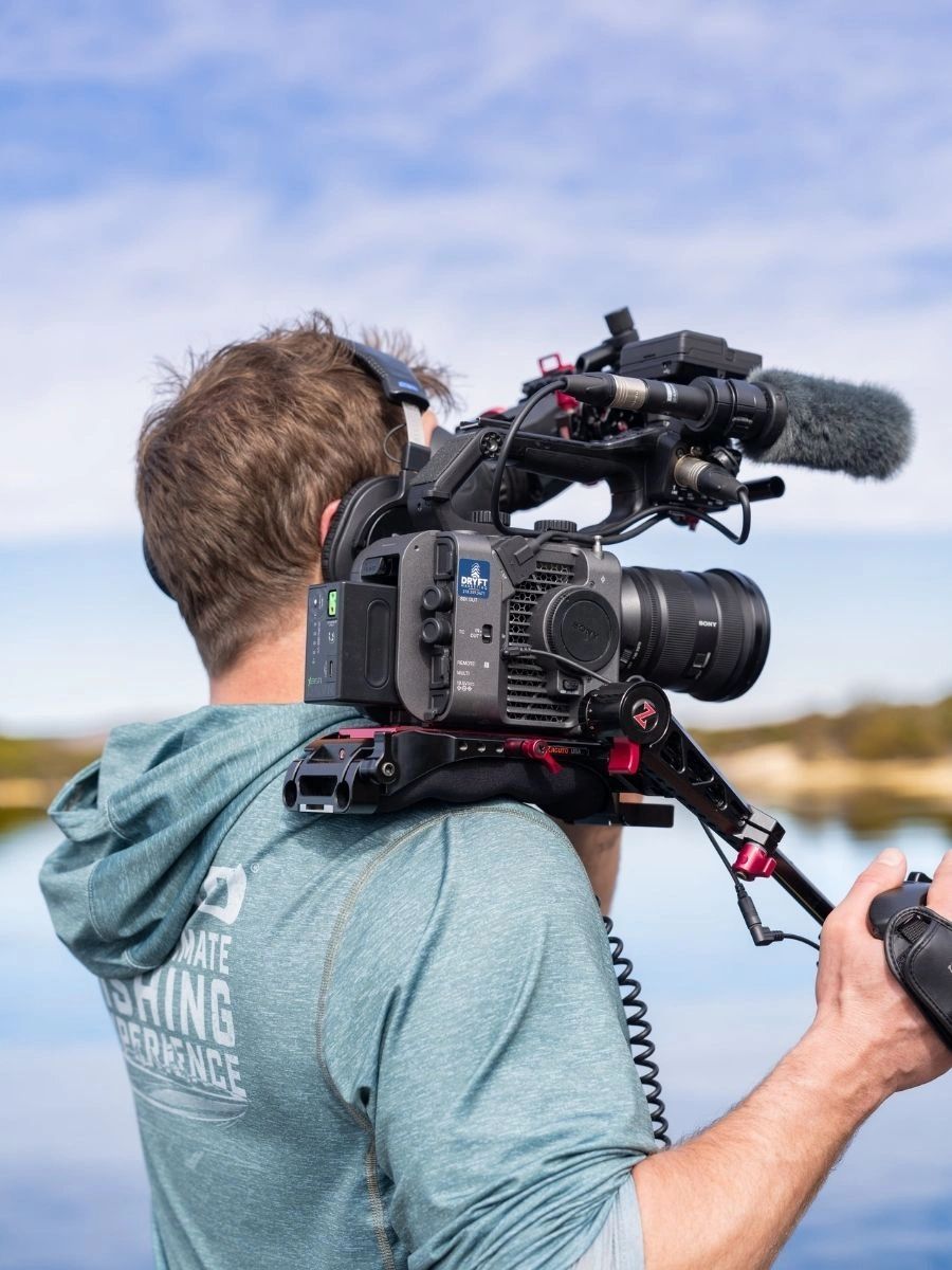 Person holding a professional video camera outdoors.