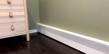 White baseboard heater along a green wall with dark wooden floor.