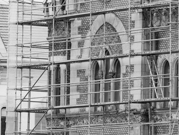 Close-up of a historic building under renovation, featuring a decorative stone arch