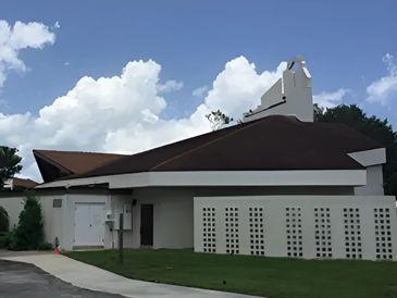 White walls and red roof of a building and a lawn in front of it