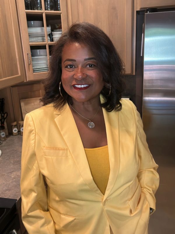 Smiling woman in yellow suit standing in a kitchen.