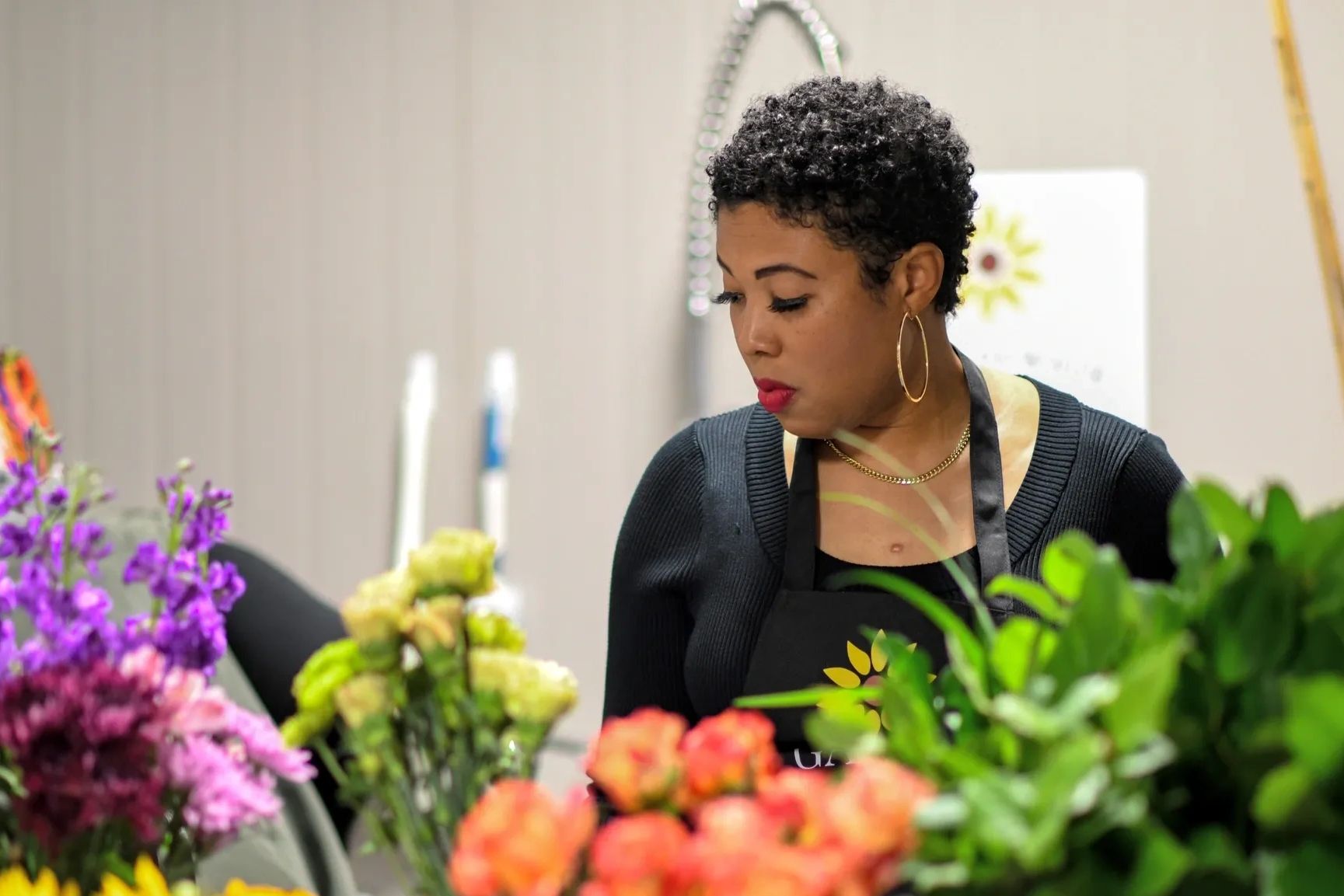Woman arranging colorful flowers in a shop or studio.