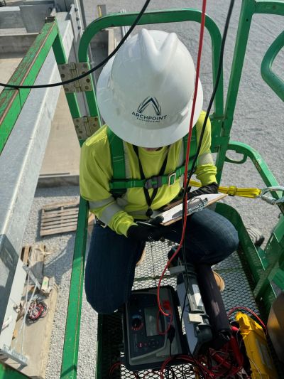 Worker in safety gear inspecting equipment on a lift platform.