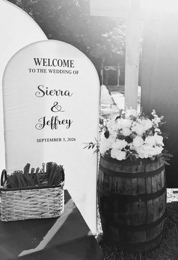 Wedding welcome sign for Sierra and Jeffrey with flowers on a barrel.