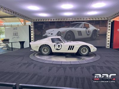 Classic white race car on display with matching backdrop.