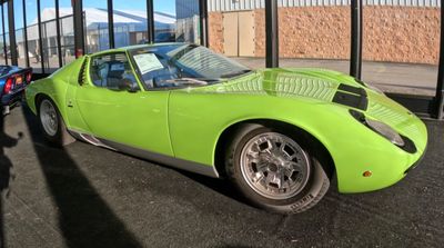 Green vintage sports car parked indoors.