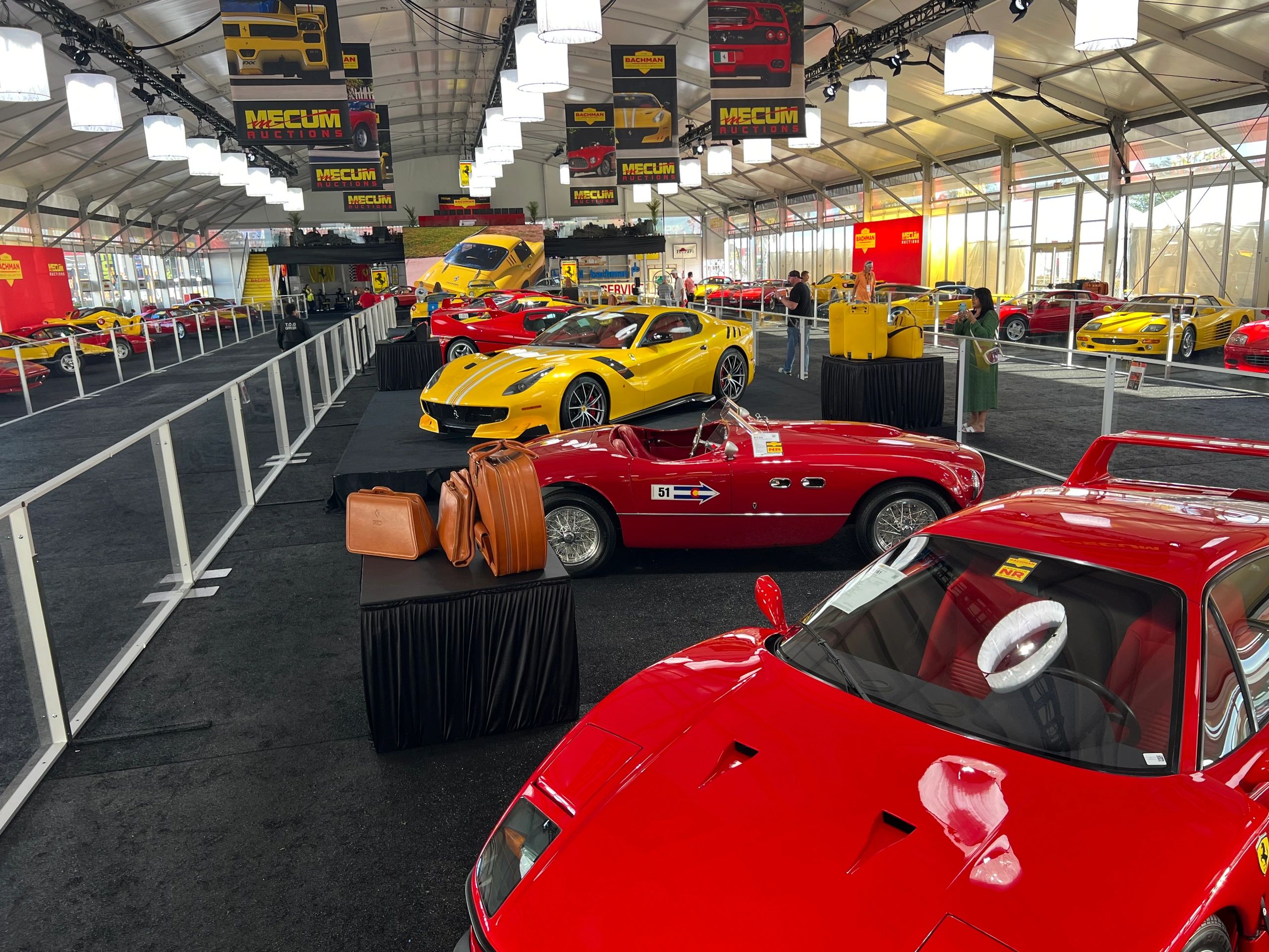 A luxurious car auction featuring classic and modern Ferraris in a well-lit tent.