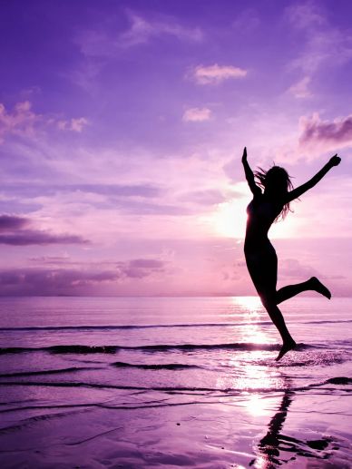 Silhouette of a person jumping at sunset on the beach.