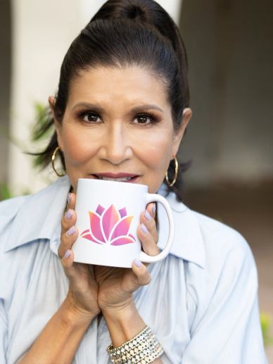 Woman holding a white mug with a lotus design.