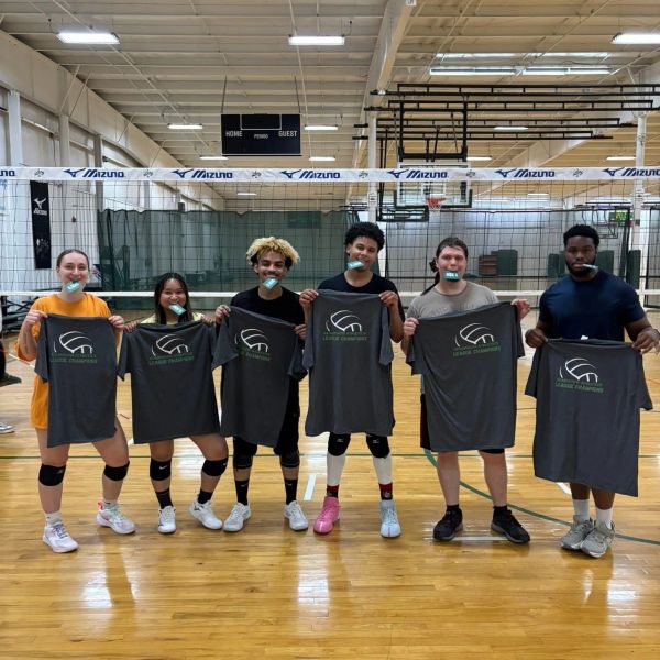 Six volleyball players holding gray shirts in a gym.