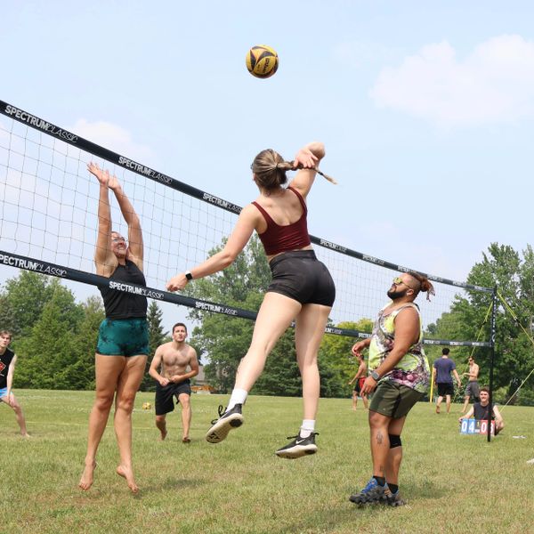 People playing volleyball outdoors on a sunny day.