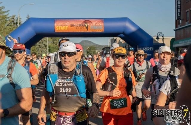 Runners starting the Sinister 7 Ultra race under a blue inflatable arch.