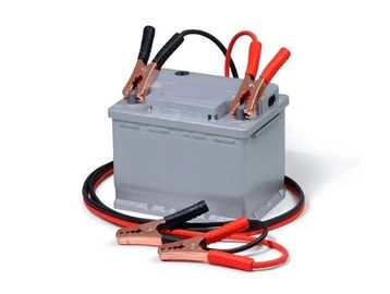 Car battery with jumper cables attached for charging or jump-starting.