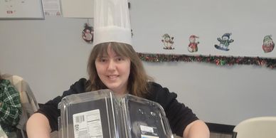 Person holding empty plastic containers over a salad bowl.