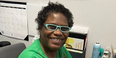 Person smiling while working on a tablet at a desk.