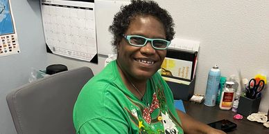 Person smiling while working on a tablet at a desk.