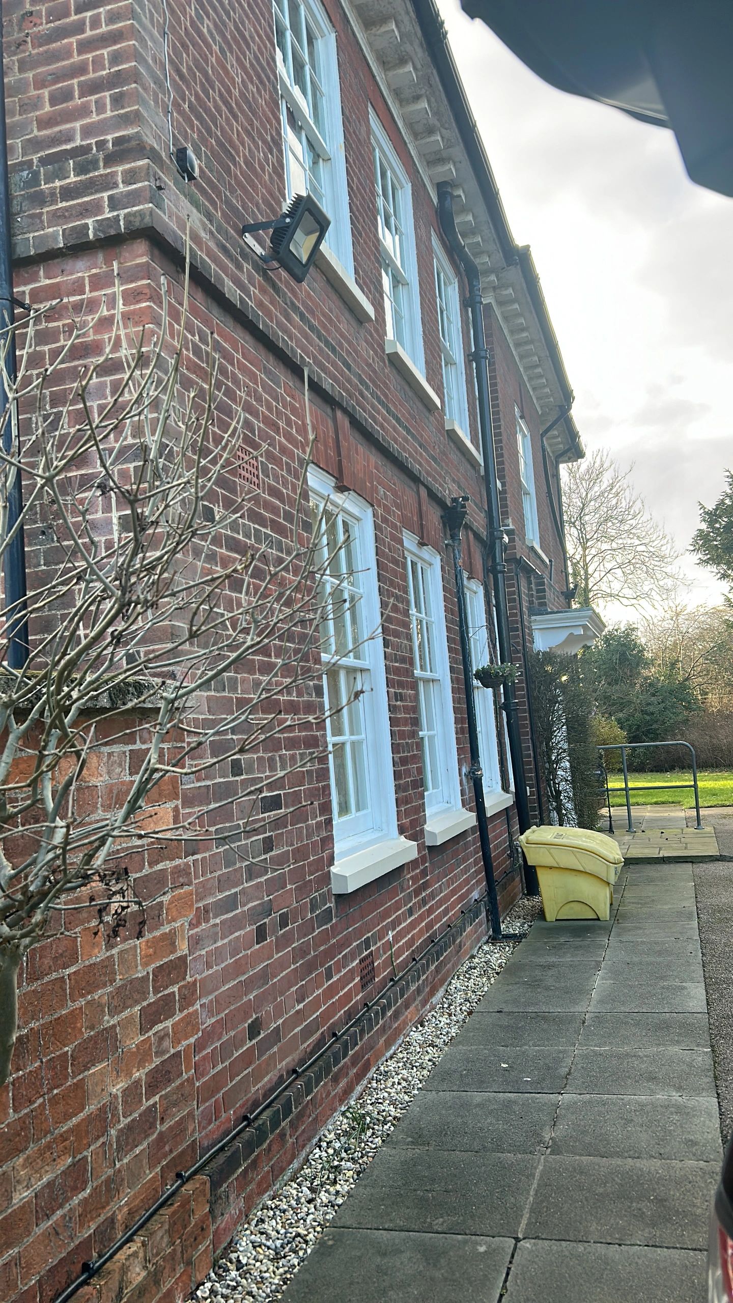 Brick house exterior with white windows and yellow bin.
