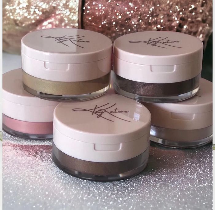 Five jars of Kay Katore cosmetic products arranged on a glittery surface.