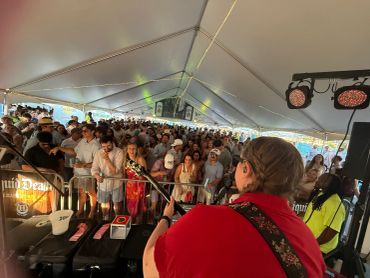 Musician performs for a crowded tent audience.