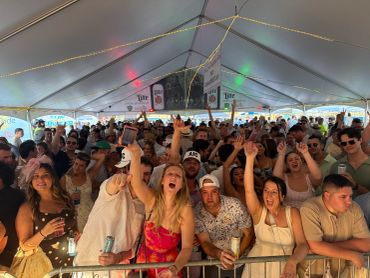 Crowd enjoying music festival under a large tent.
