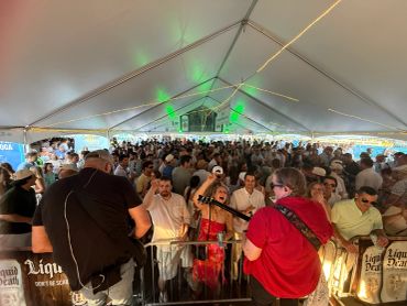 Large crowd enjoying live music under a tent.
