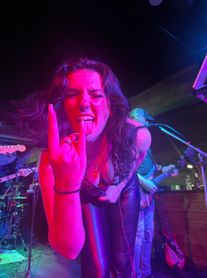 Energetic woman at a live rock concert making a rock hand gesture.