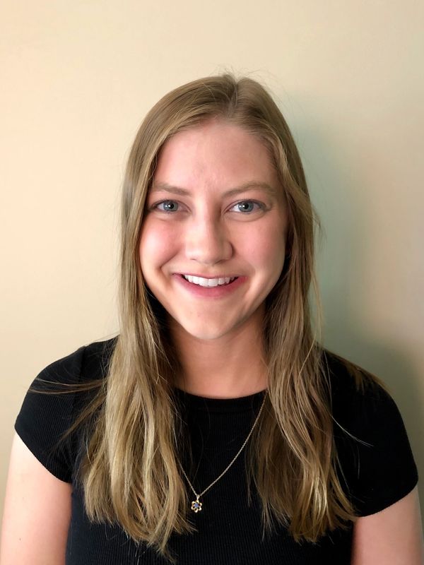 A smiling young woman with long blonde hair and a black top.