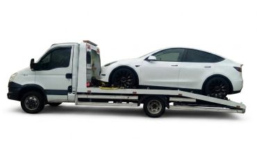 White sedan being loaded onto a flatbed tow truck.