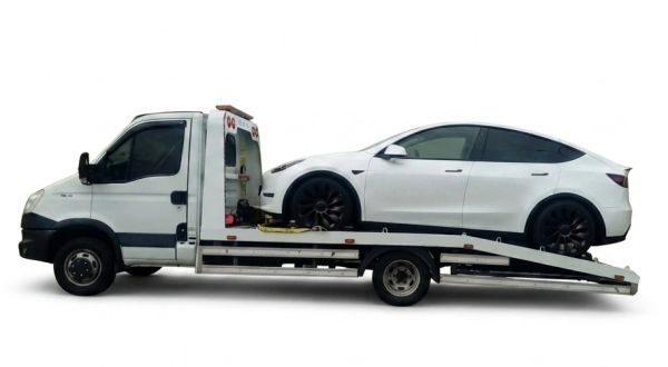 White sedan being loaded onto a flatbed tow truck.