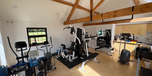 Bright home gym with wooden beams and exercise equipment.