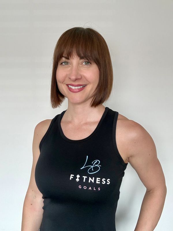 A smiling woman in a black fitness tank top against a plain background.