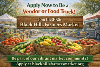Colorful produce baskets at Black Hills Farmers Market with vendor sign.