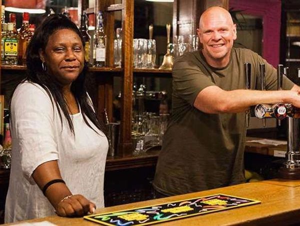 two smiling people waiting at the bar