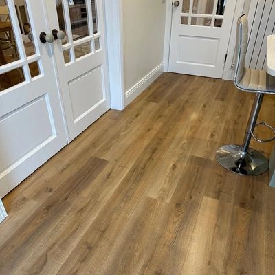 Clean wooden floor with white doors and a modern chair in a cozy room.