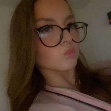 Young woman with glasses making a pouty face in a cozy indoor setting.