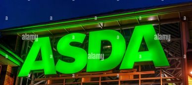 Bright green ASDA store sign illuminated at night.