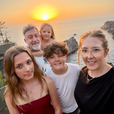 Family selfie at sunset by the rocky seaside.