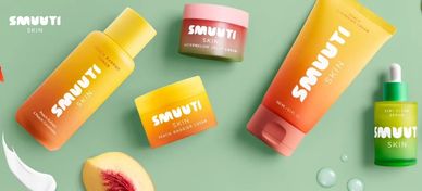 Colorful Smuvti Skin skincare products arranged on a green surface with peach slices.