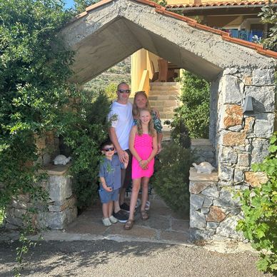 Family posing under a stone archway at a sunny entrance.